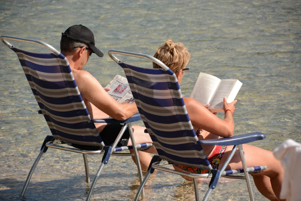 Un coupe sur des transats, lisant au bord de la rivière