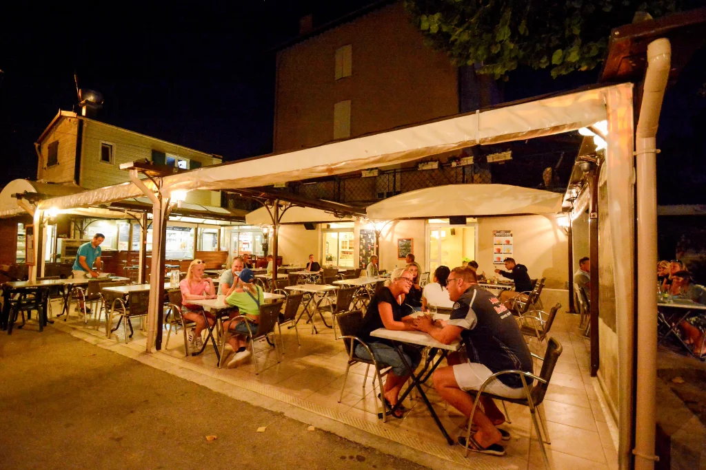 Terrasse du restaurant, le soir avec quelques personnes profitant d'un repas
