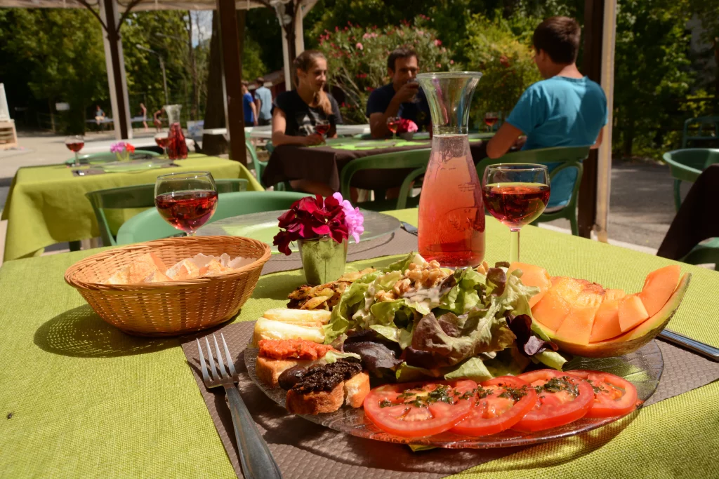 Table dressée du restaurant, avec une assiette de salade composée et deux verres de vin