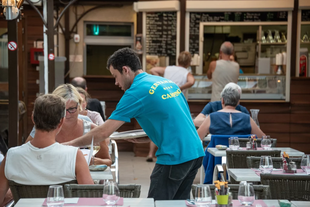 Un serveur s'occupe du service à table à la terrasse du restaurant