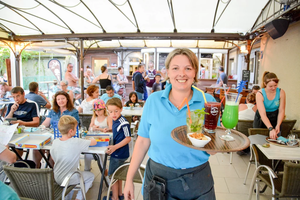 Serveuse souriante devant la salle du restaurant